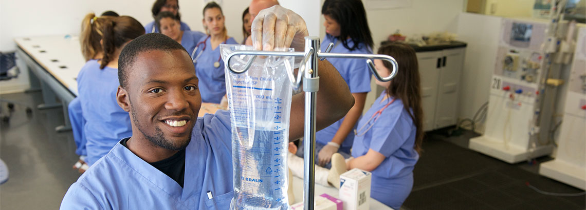 Male nursing student adjusting an IV bag.