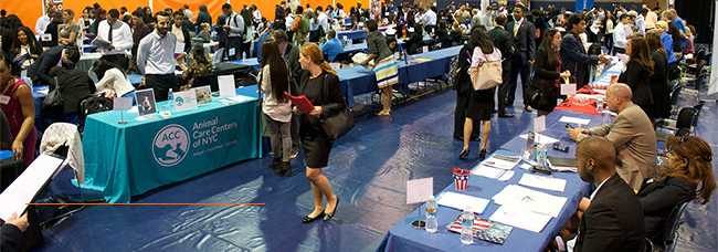 students walking through large room with people behind tables representing different organizations