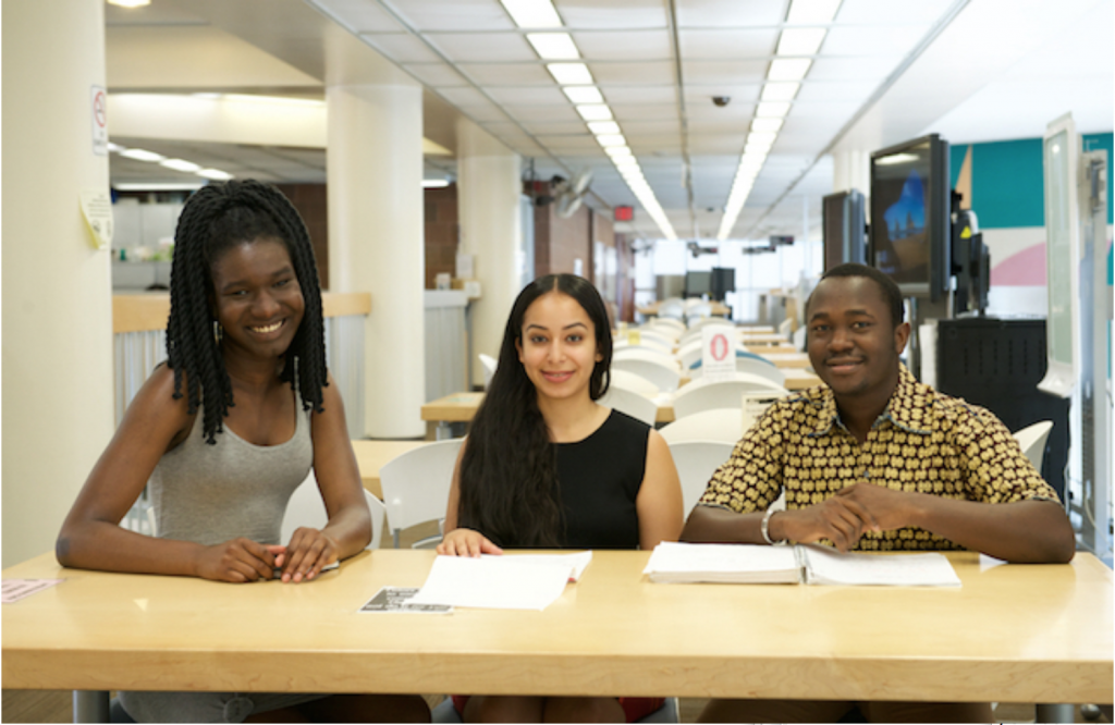 three students sitting at library table
