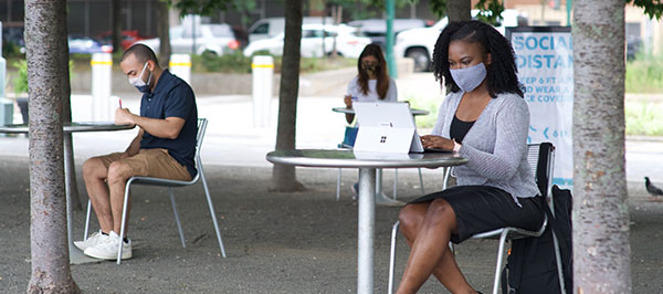students at tables on campus wearing face masks