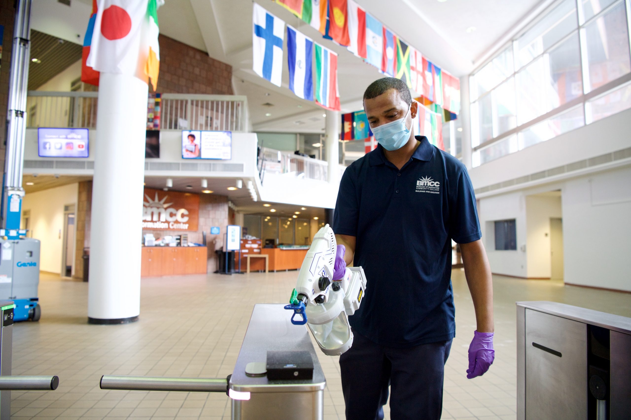 An essential worker enacts safety protocols at a BMCC entrance.