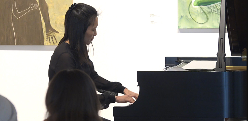 woman playing grand piano in art gallery.