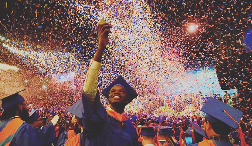 student in cap and gown celebrating at graduation ceremony