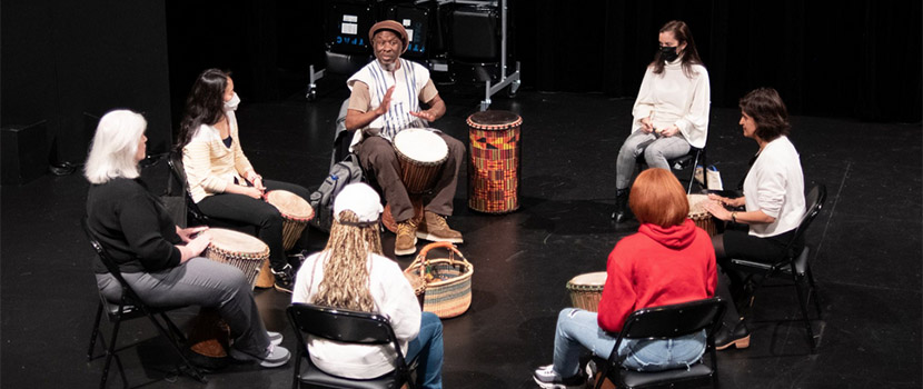 students and drum master in a circle playing the African drums