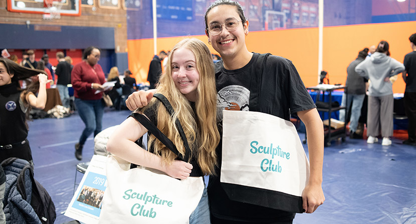 Two students holding Sculpture Club tote bags