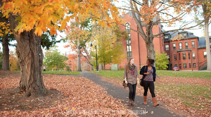 Mt. Holyoke College campus with two students walking amidst autumn scenery