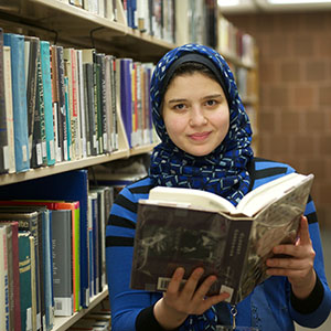 student in library holding book