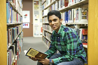 student reading a book in the stacks