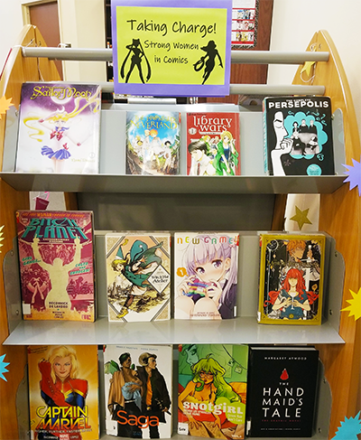 Display of comics in the library, featuring strong female characters